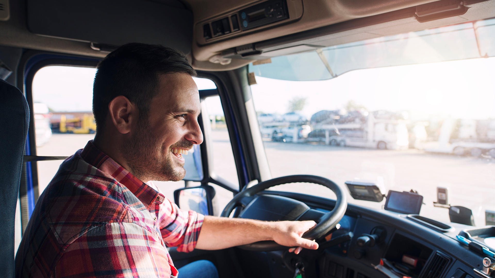 A semi truck driver, hand on the wheel