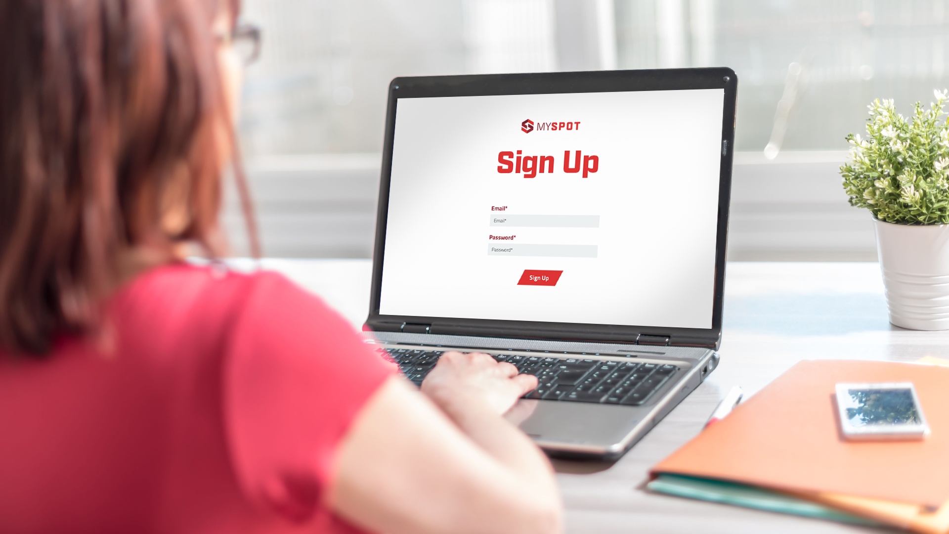 A person with an open laptop on a desk - on the laptop screen is the sign up page for Spot TMS.