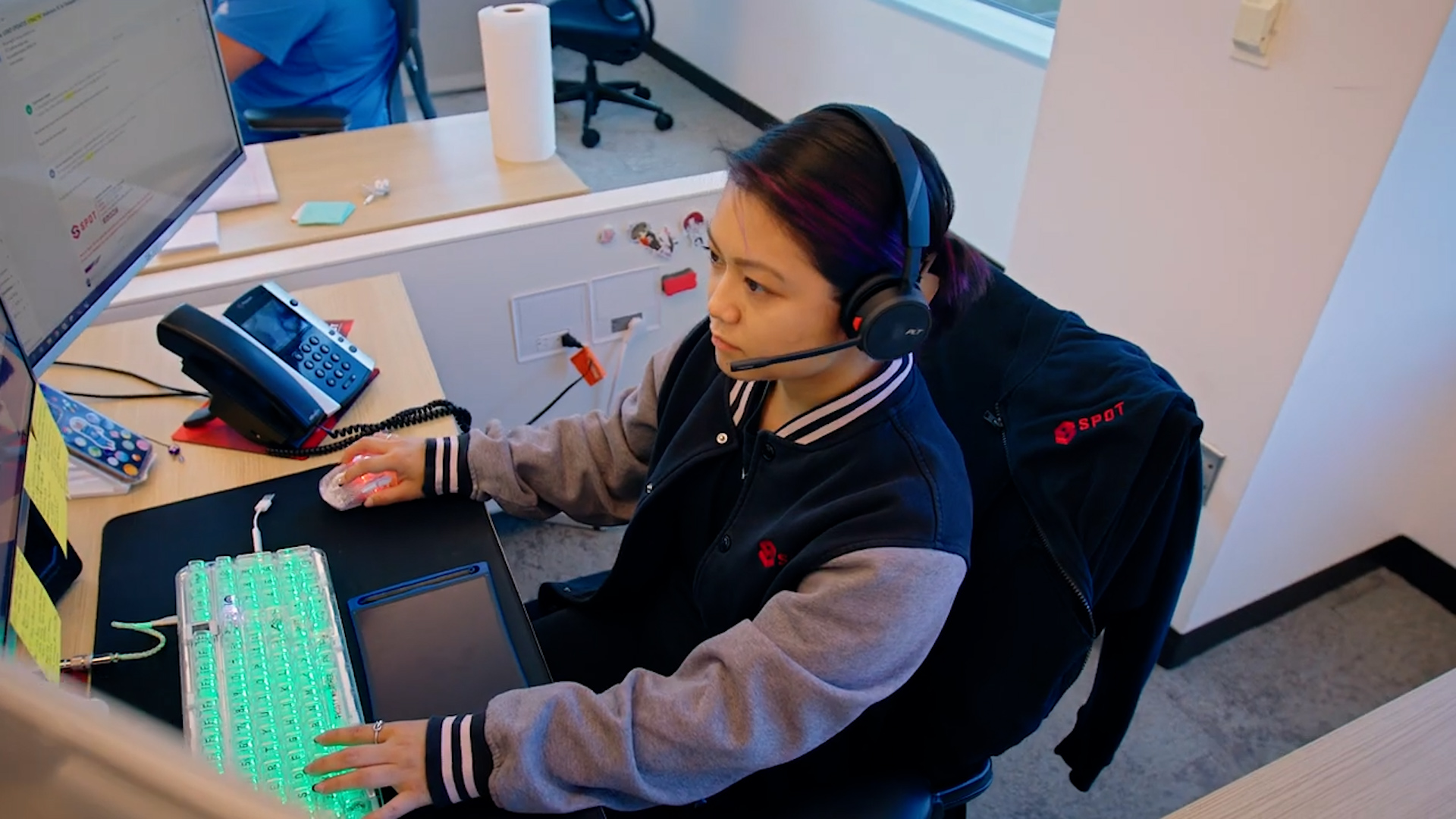 A MySpot TMS employee sitting at a desk and on a headset talking to a shipper, carrier, or driver