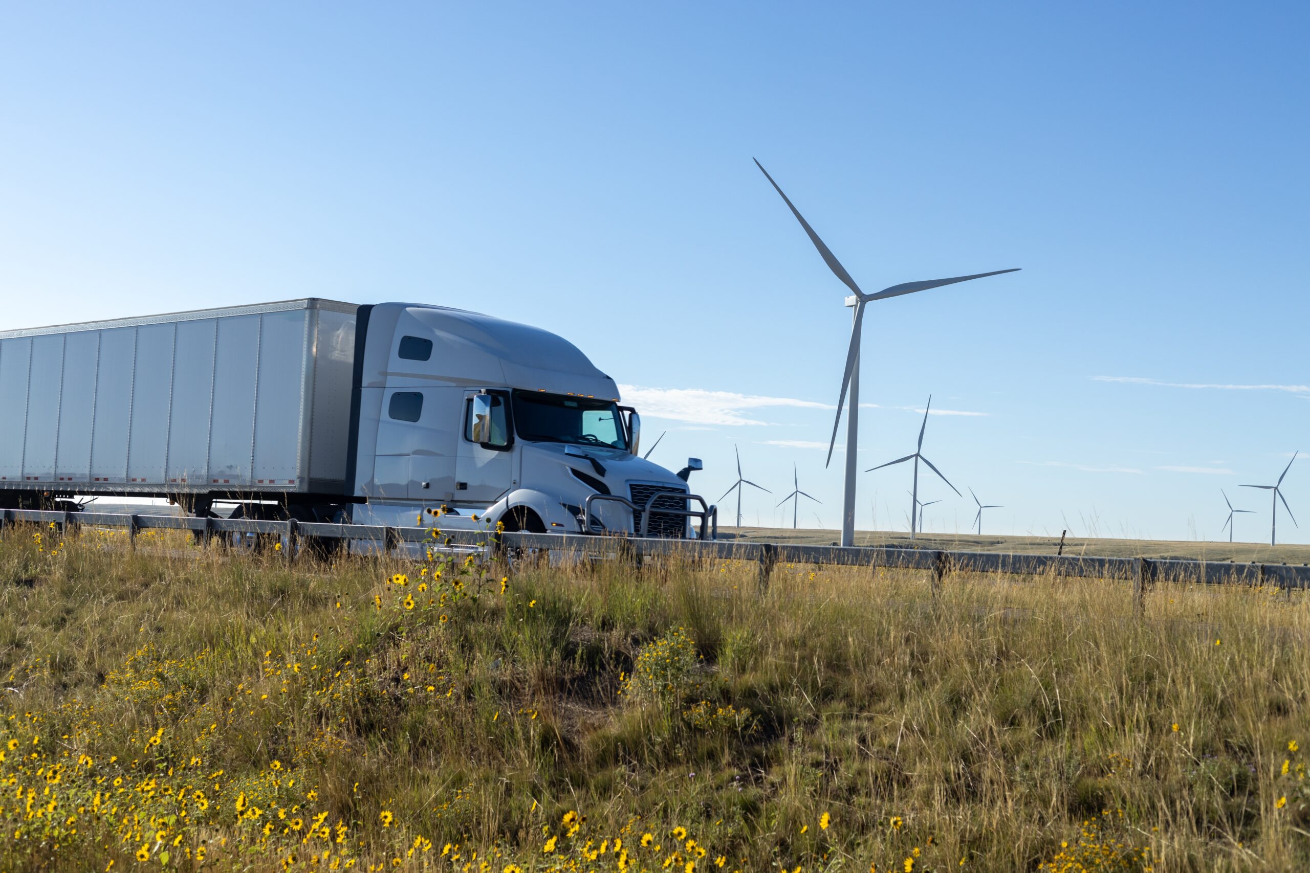 Renewable,Energy,On,The,Road:,Semi-truck,Driving,Past,Wind,Turbines